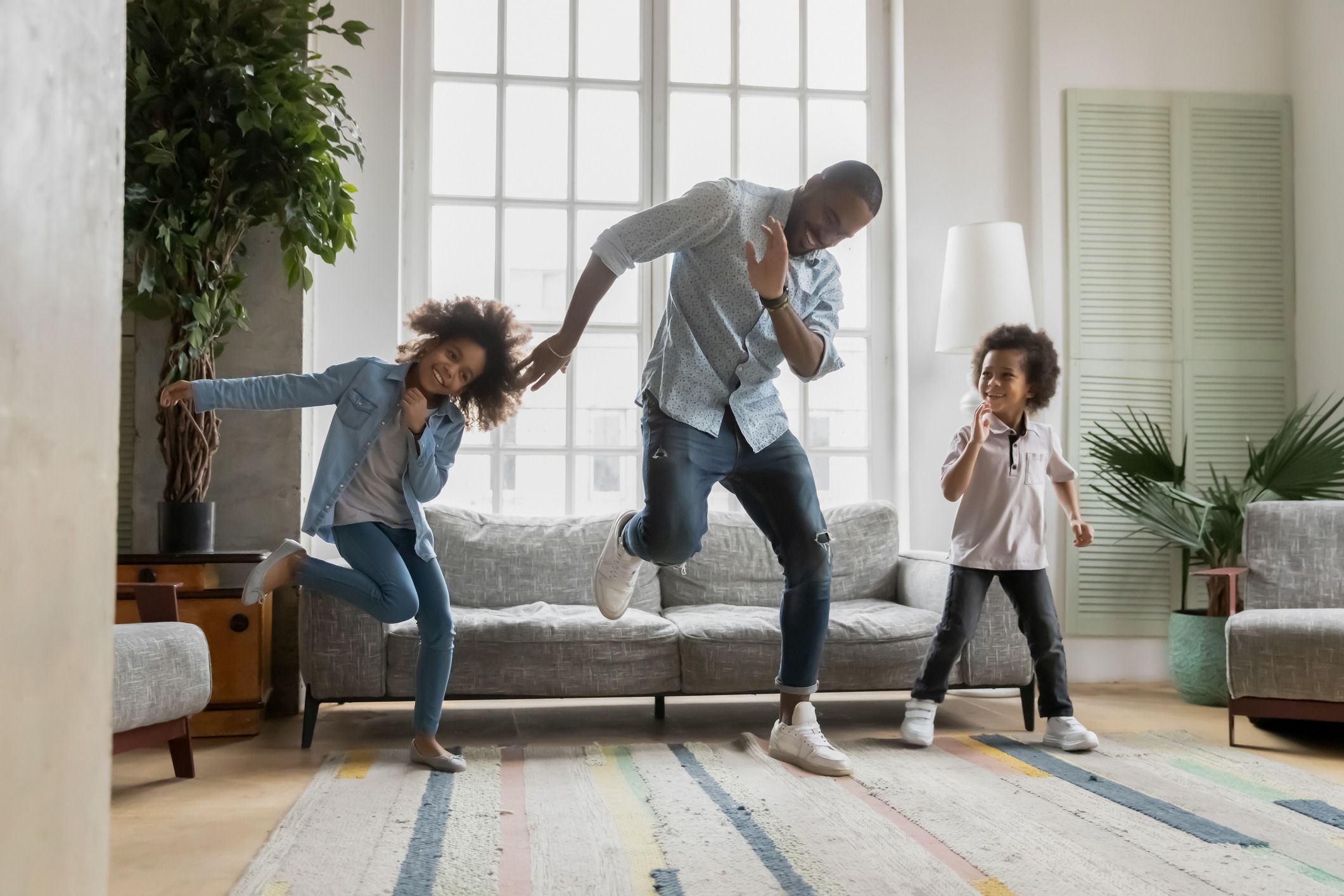 Happy african american father showing funny dancing moves to kids.